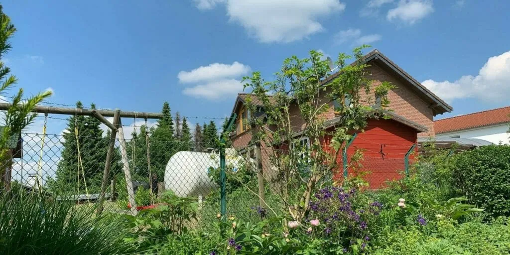 Weißer oberirdischer Flüssiggastank im Garten vor einem Einfamilienhaus