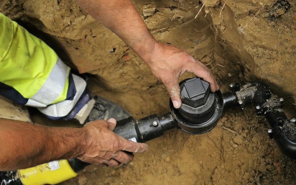 Handwerker verlegt Flüssiggasleitung in einem Graben